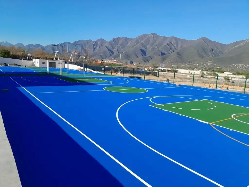 Cancha deportiva pintada en azul y verde con montañas al fondo