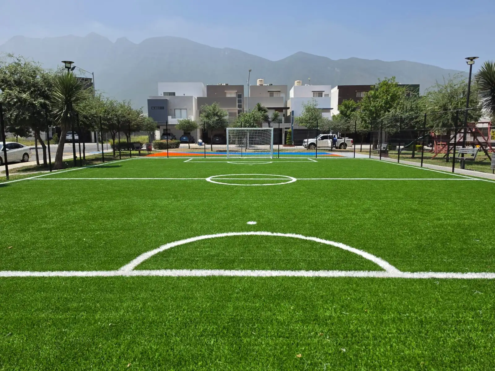 Cancha de fútbol con pasto sintético y las montañas de Monterrey al fondo