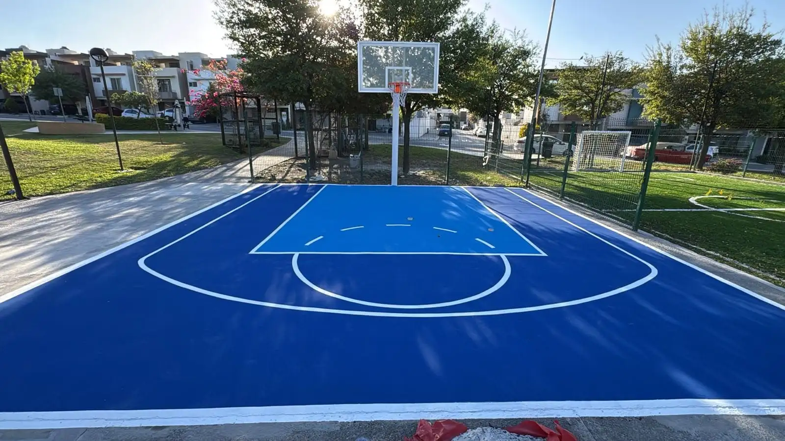 Cancha de básquetbol pintada en azul dentro de un fraccionamiento